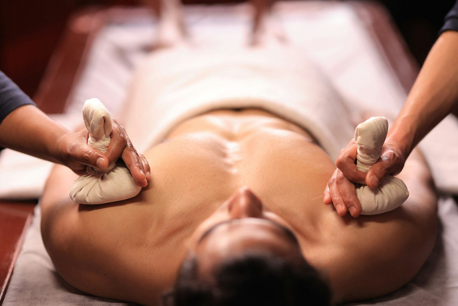 A practitioner pressing warm herbal compress balls onto a client's chest